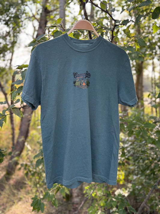Campfire Social Club t-shirt on a hanger against a natural forest background