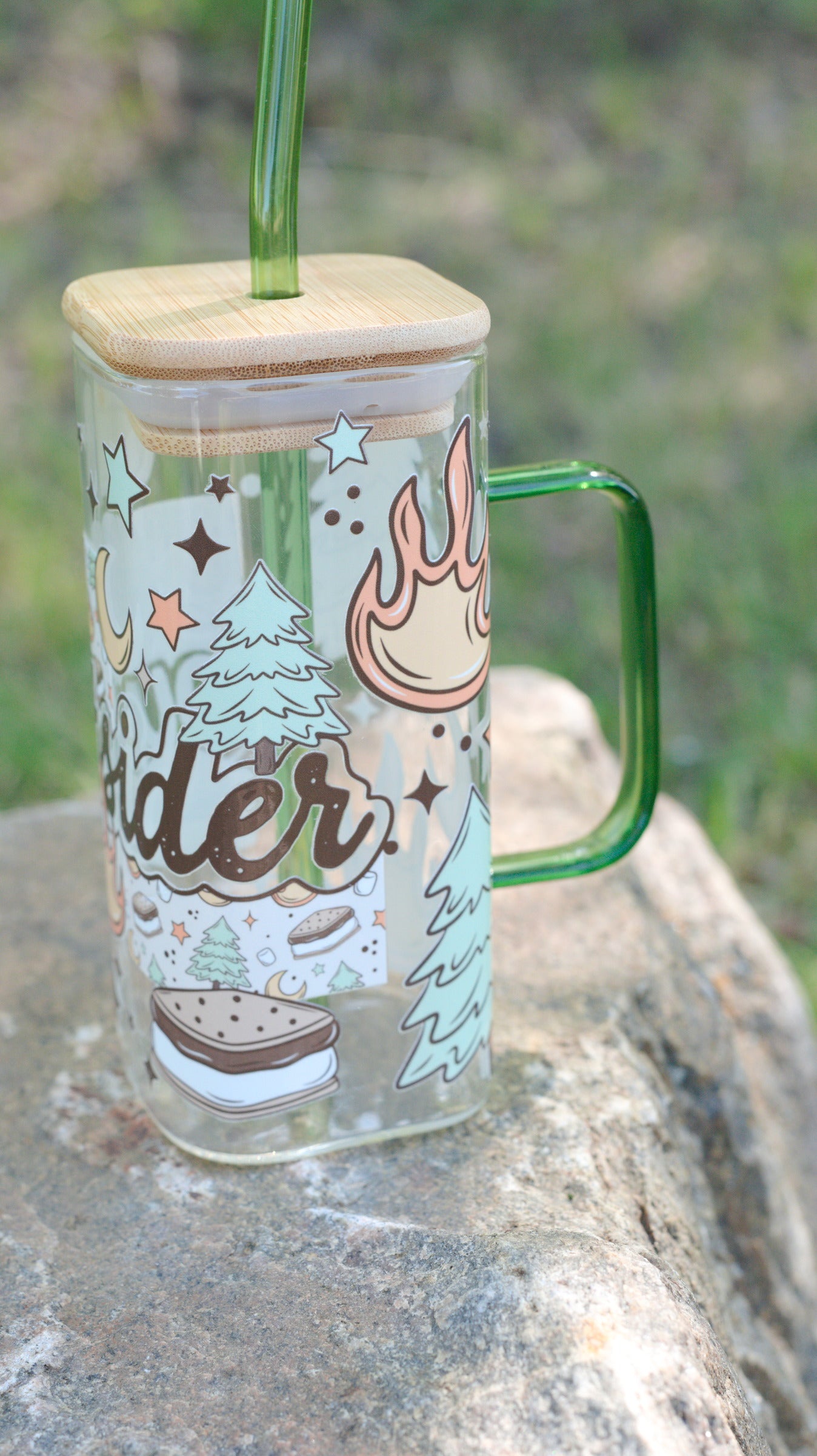 Glass mug with handle and wooden lid on a rock with a natural background