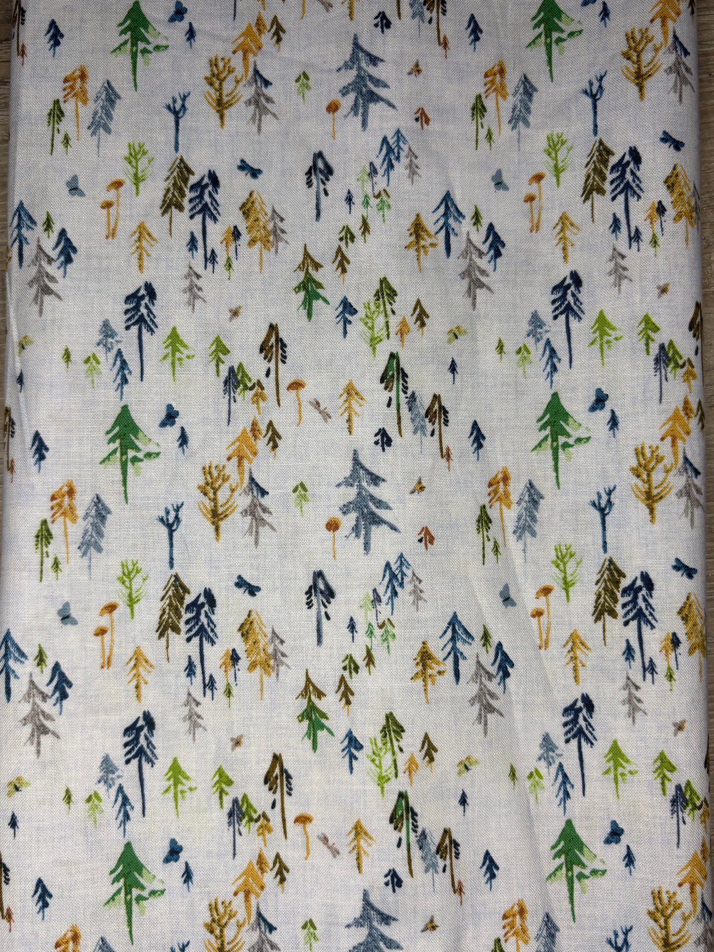 Fabric with a pattern of stylized trees in various colors on a neutral background