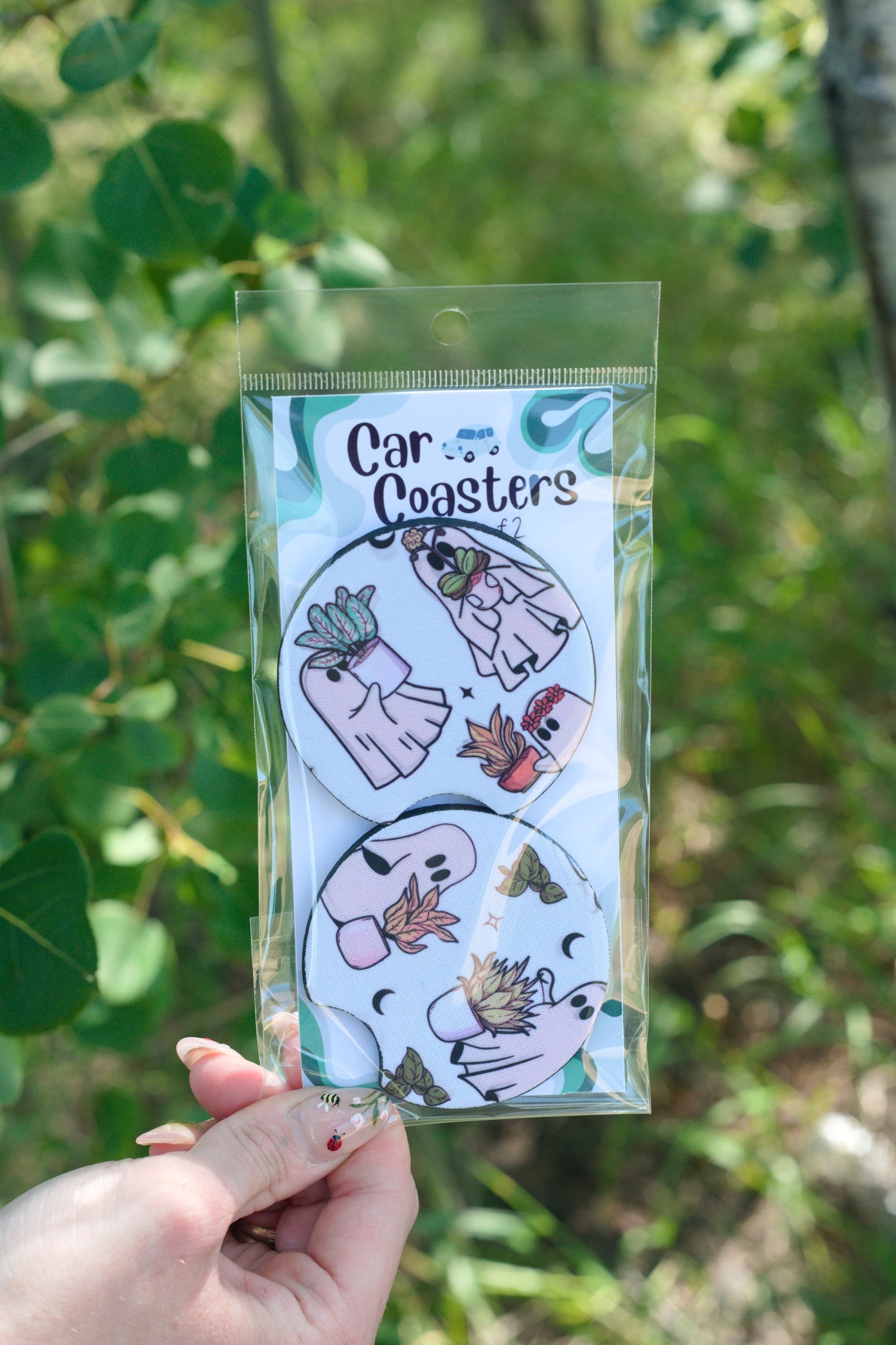 Boo-tanical halloween car coasters held in front of a natural background